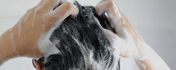 Kvinde vasker håret med shampoo uden silikone